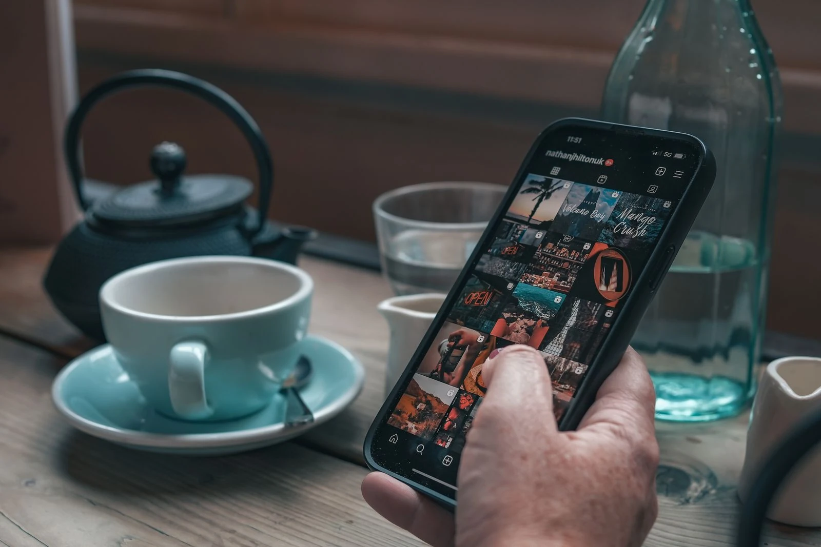 Hand holding phone showing social media content grid