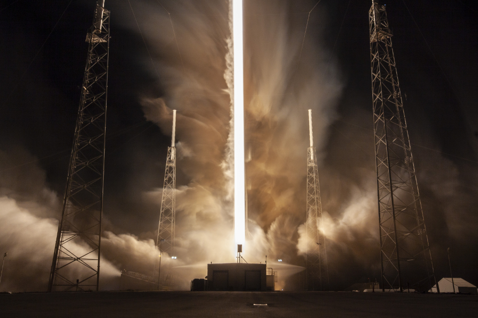 Rocket launching into the night sky in a blaze of engine fire and smoke