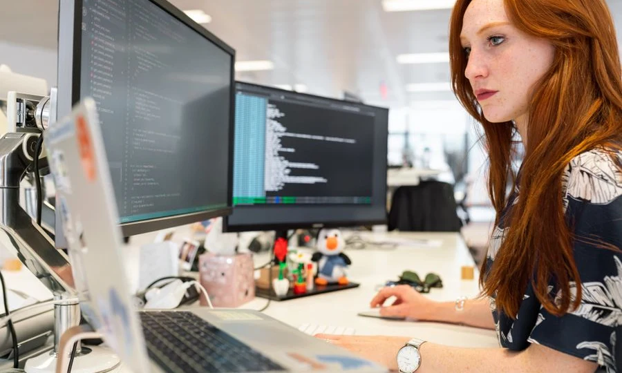 Software engineer coding an AI SaaS platform on dual monitors