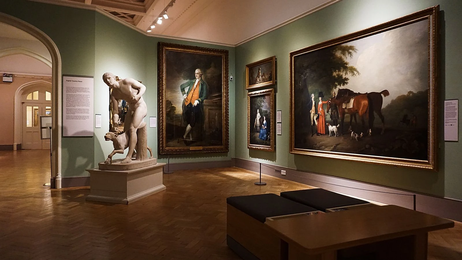 Elegant museum gallery room with gold-framed paintings and marble sculpture