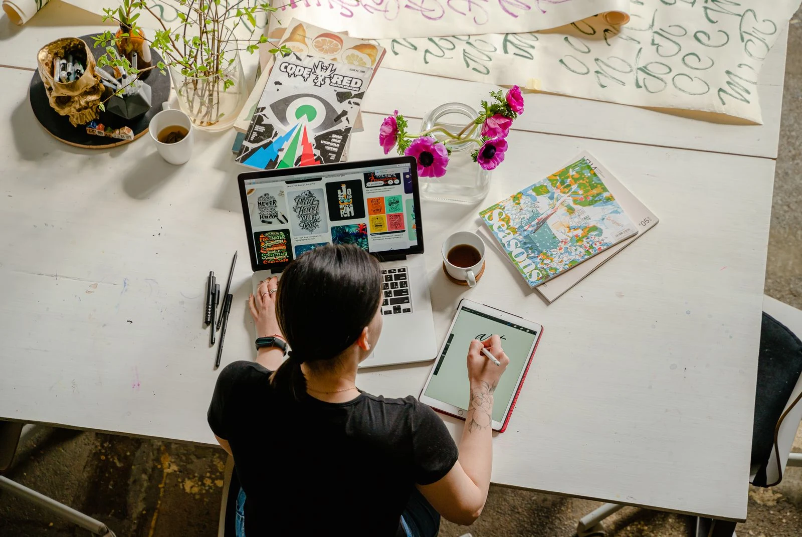 Digital creator designing artwork with a laptop, tablet, and stylus