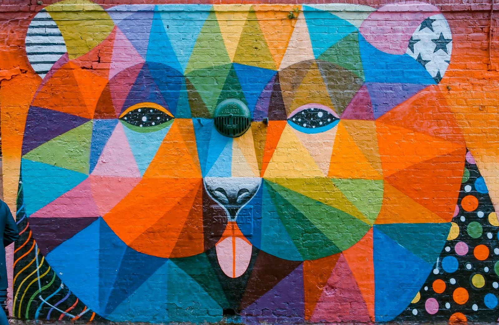 Colorful geometric bear mural painted on an outdoor brick wall