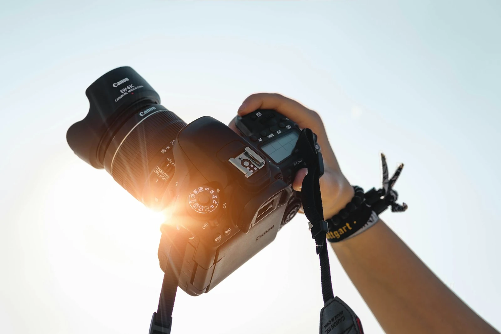Photographer silhouette holding a professional camera against bright light