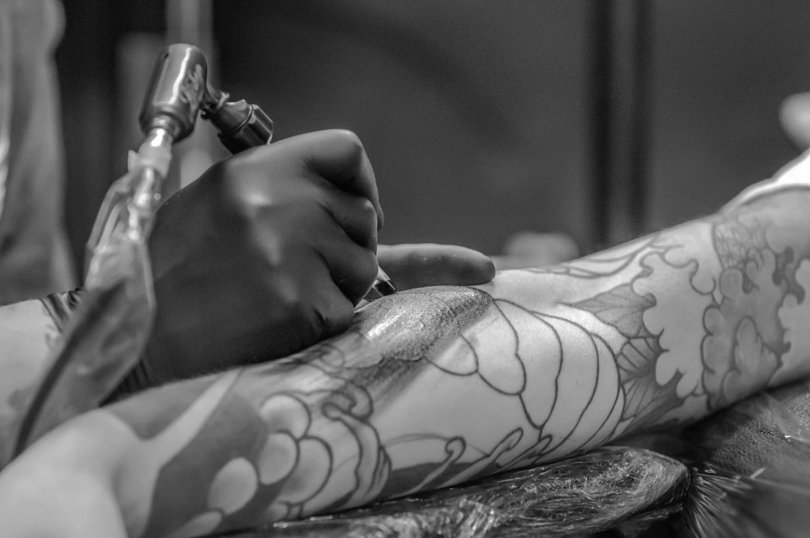 Tattoo artist applying intricate linework with a tattoo machine