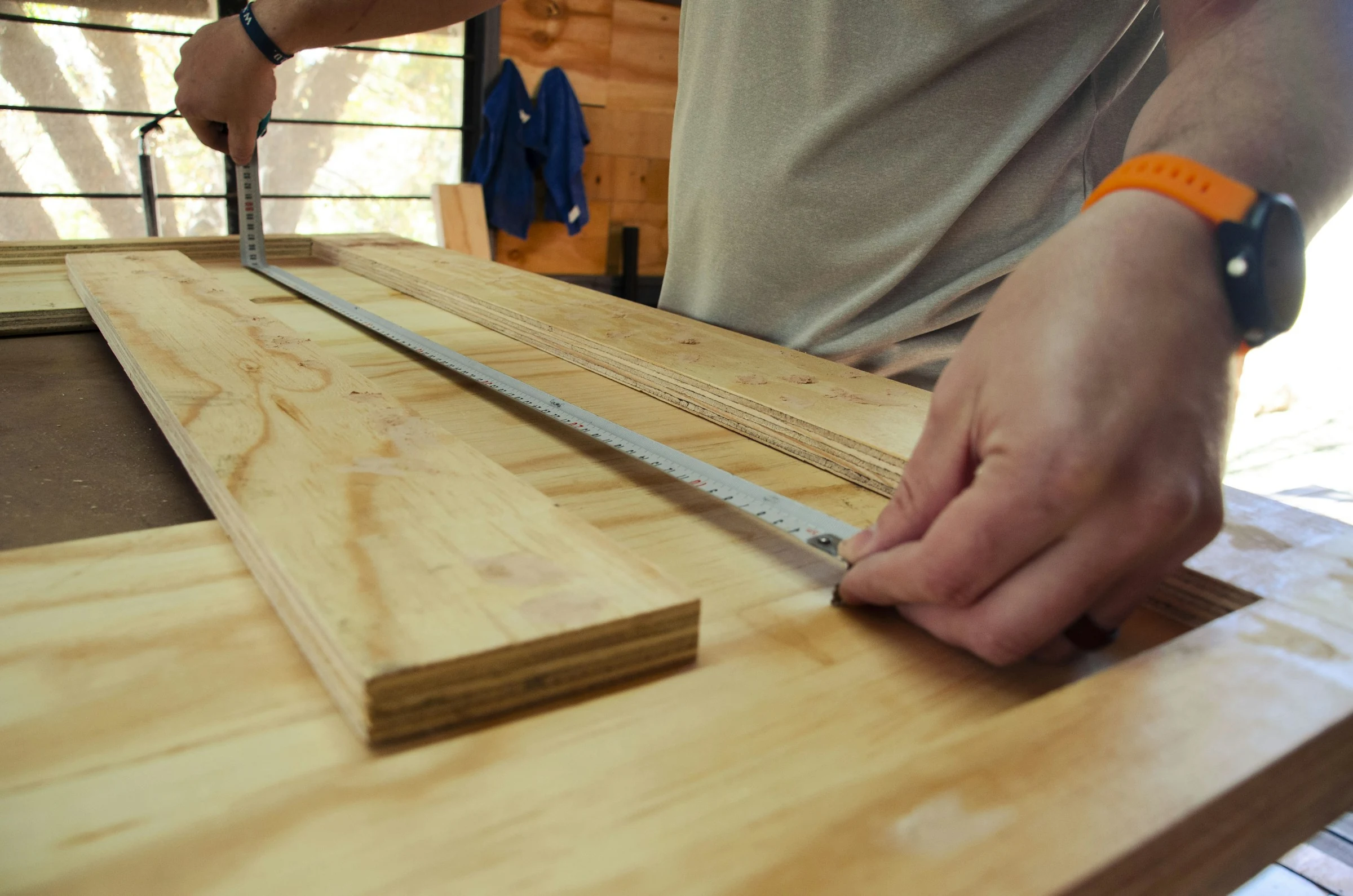 Carpenter measuring plywood pieces in a woodworking workshop