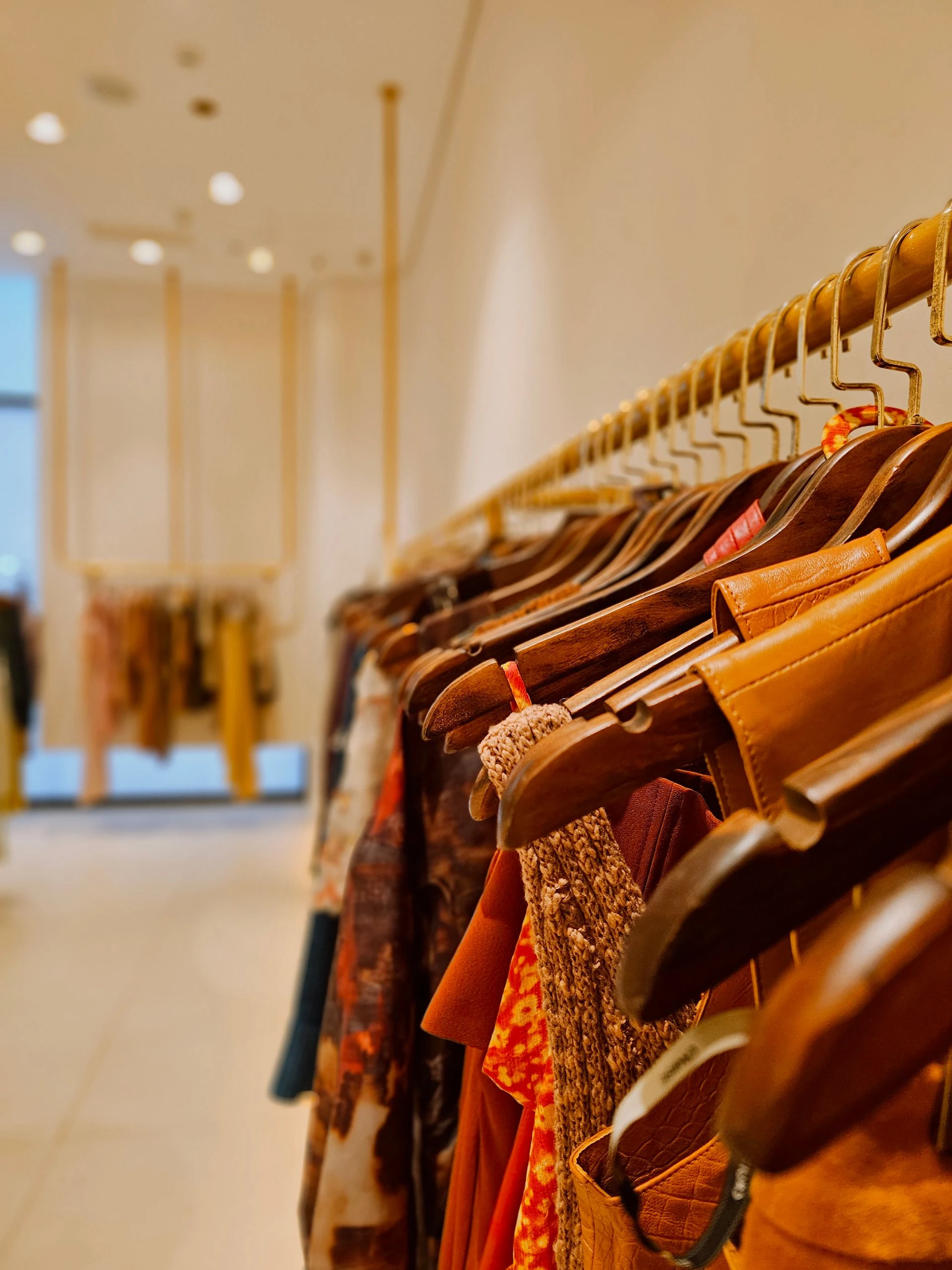 Premium clothing rack with tailored garments on wooden hangers in a boutique