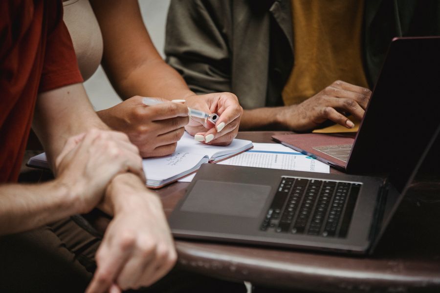 Hands reviewing compliance documents alongside a laptop